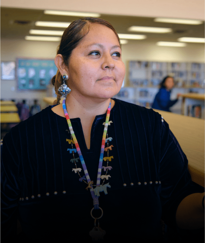Person in library with colorful necklace.